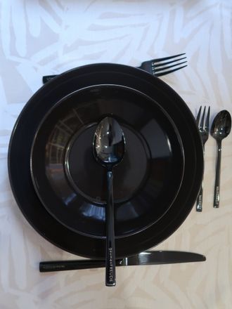 Tasse und Besteck auf einem gelben Teller