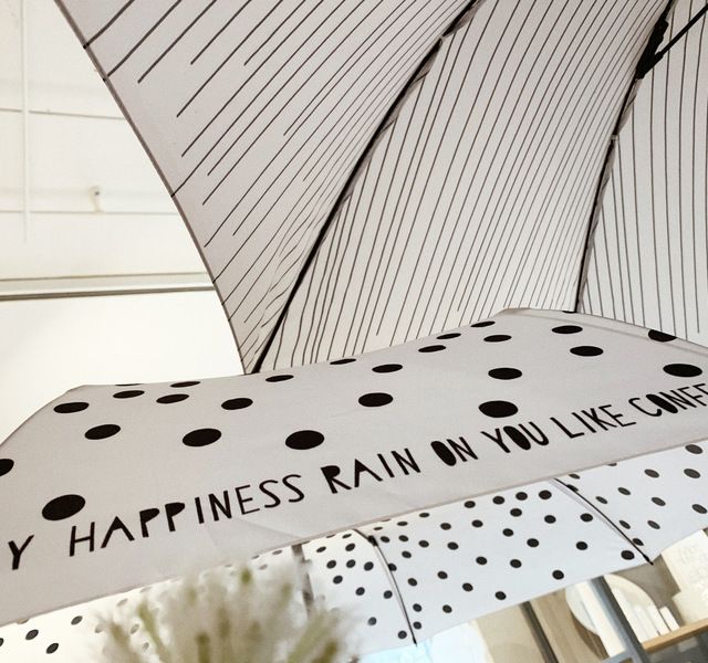 Weiße Regenschirme mit schwarzem Muster und Schriftzug